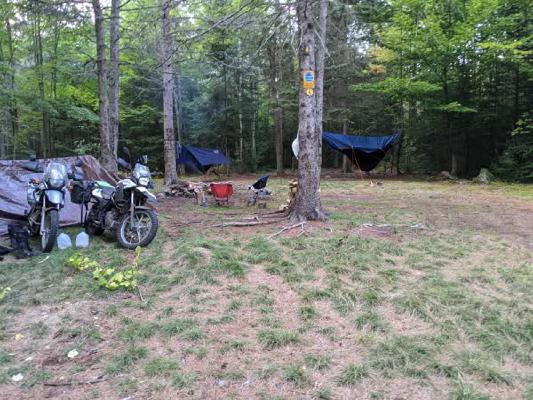 2 bikes, 2 hammocks, 2 brothers at a campsite in the woods.